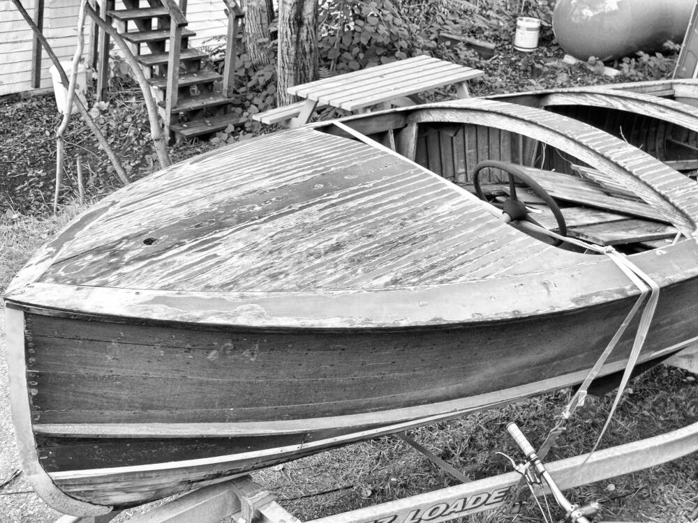 A small wood boat in need of restoration and refinishing sits near the Indian River in Port Carling, Muskoka, Ontario.