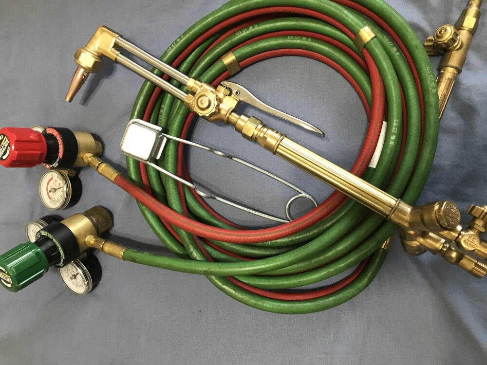 Oxyacetylene cutting torch, fuel and oxygen hoses and regulators are pictured with a spark igniter to reference structural steel construction in Muskoka, Ontario.