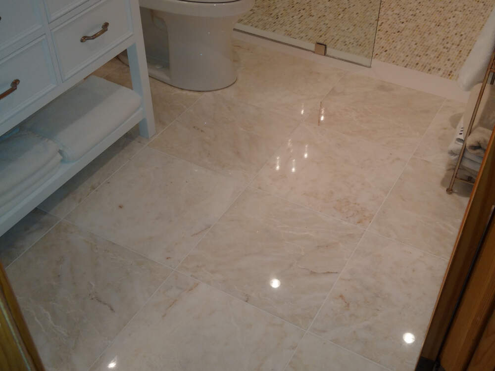 Polished white marble flooring tiles in 18-inch by 18-inch square format are installed on the floor of a luxury home renovation in Muskoka, Ontario.