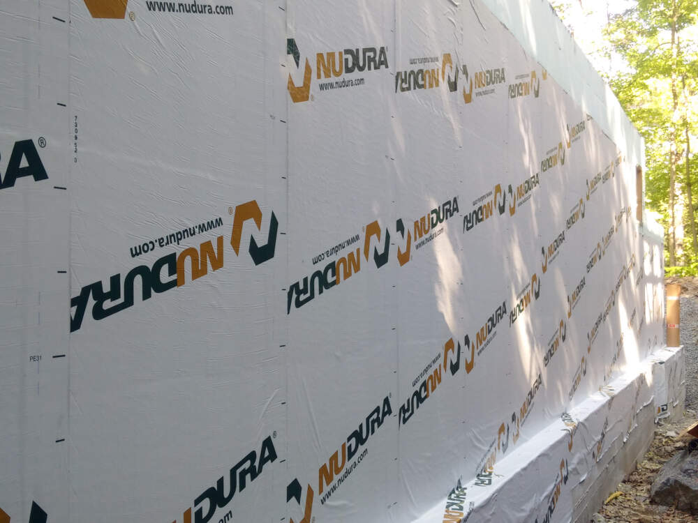 An insulated concrete form (I.C.F.) foundation wall with self-adhering waterproofing membrane applied neatly is shown on a home building project in the Township of Muskoka Lakes, Muskoka, Ontario.