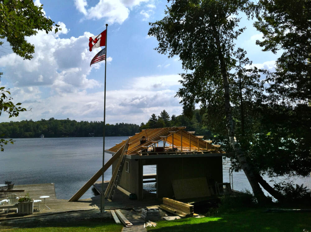 Wood framing carpenters and general contractors are in the process of building a wood frame roof structure on a boathouse construction project on Lake Rosseau, Muskoka, Ontario.