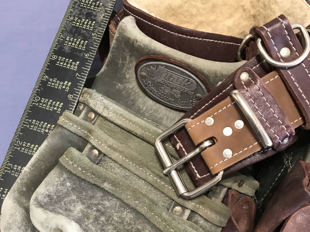 A worn carpenter's belt and rafter square are framed to reference the building and construction trades in Muskoka, Ontario.