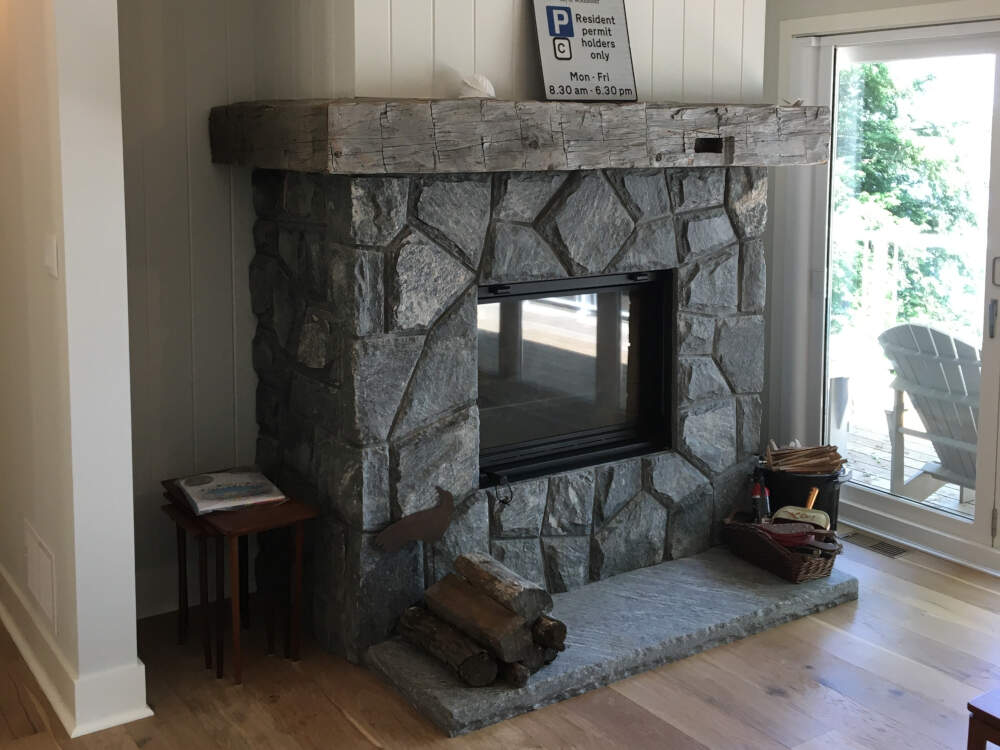 A wood-burning zero clearance fireplace insert can be supported by wood frame construction and finished with thin stone masonry veneer, without needing a full concrete or masonry foundation.