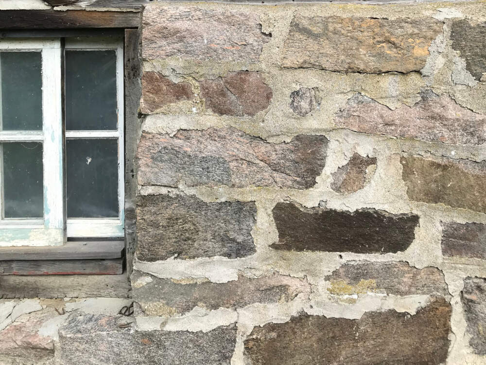 A traditional fieldstone masonry foundation wall provides a stable base for a timberframed barn in Muskoka, Ontario.
