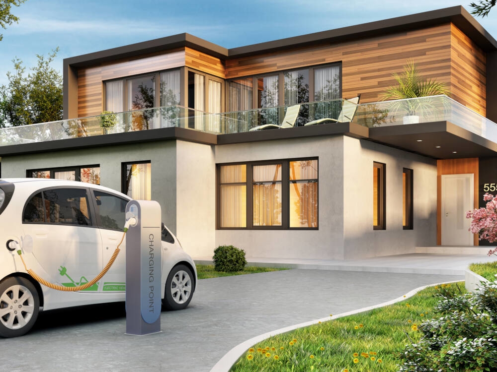 A rendering of a modern energy-efficient home design that may be a Certified Passive House is pictured with an electric vehicle and charging station in the driveway.