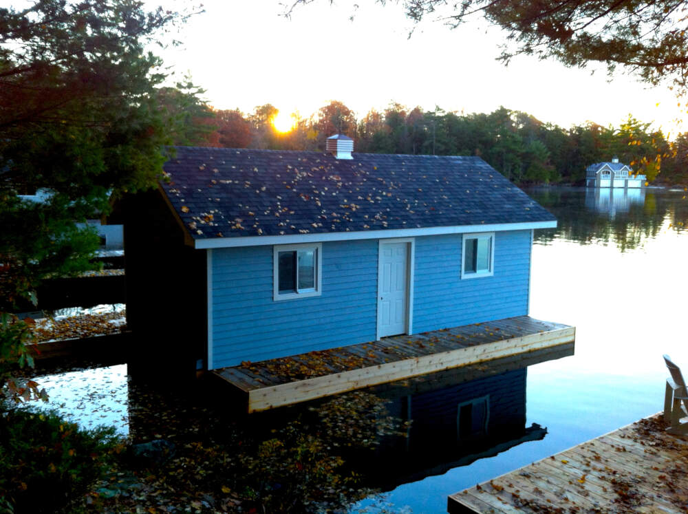 Traditional boathouse design exhibiting beveled wood siding and a cupola on Lake Muskoka.