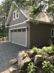 The garage design matches the exterior design of the cottage plan with vertical wood board and batten siding.