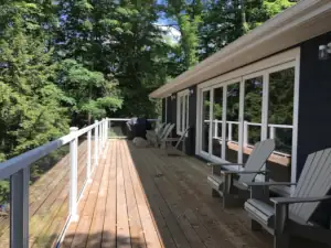 Sun shines brightly on the wood deck overlooking Lake Muskoka from this home design.