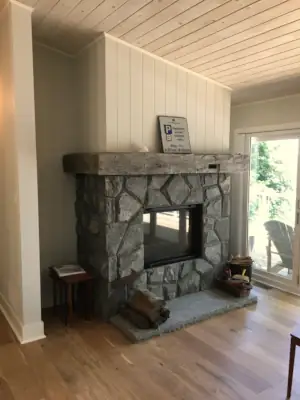 A wood-burning fireplace finished in natural granite stone veneer anchors the Living Room overlooking Lake Muskoka.