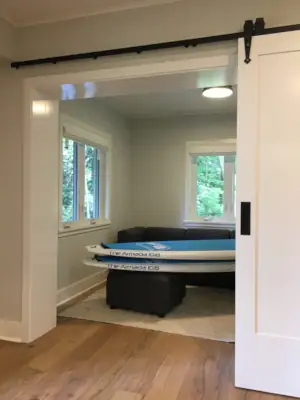 Sliding barn-style doors partition the Den and Television Room from the rest of the basement during feature movie nights in this Muskoka home plan.