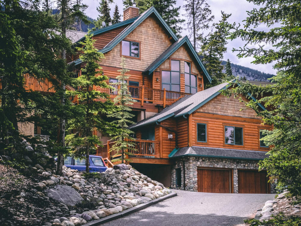 A mountain-style home featuring western red cedar and copper exterior cladding is set against a rocky mountain backrop.