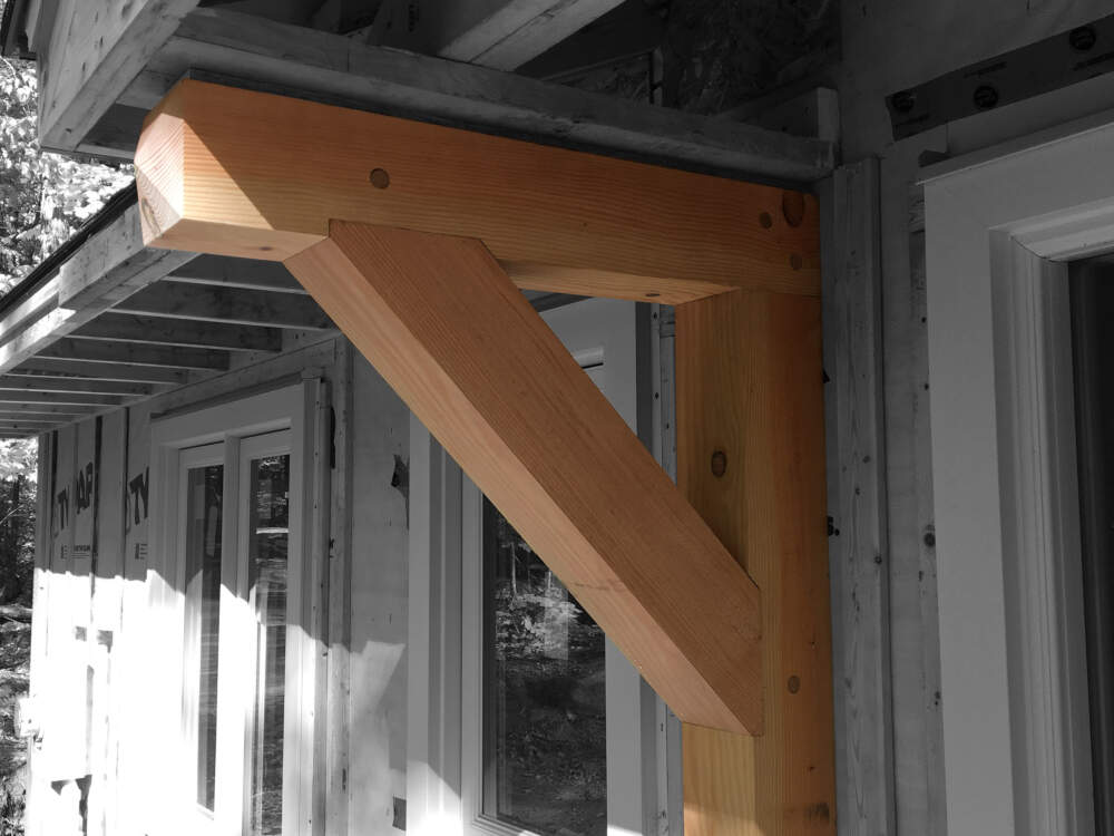 A solid douglas fir timber frame brace featuring handcut joinery supports the covered entry of a cottage design on Lake Muskoka.
