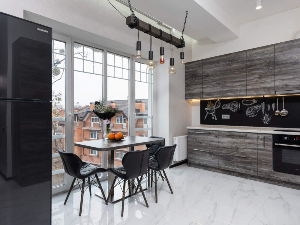 Wood paneling, modern appliances and a unique edison-bulb pendant light fixture decorate the casual dining area in a modern farmhouse kitchen design.