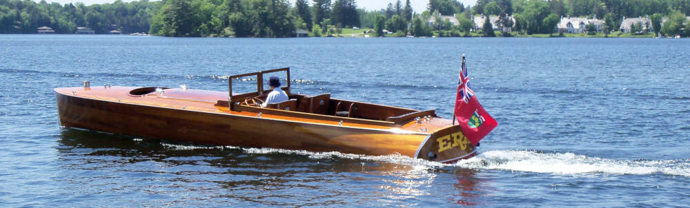 A well-maintained antique or classic wooden boat navigates the narrows at Port Sandfield on Lake Joseph, Muskoka, Ontario.
