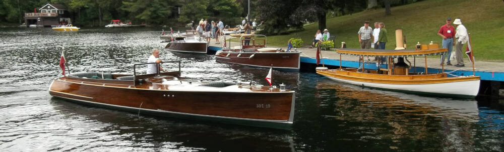 Beutiful well-maintained antique wooden boats in deep tones of brown wood and contrasting bright white paint are gathering at the locks for the Muskoka Lakes Association antique boat show in Port Carling, Muskoka, Ontario.