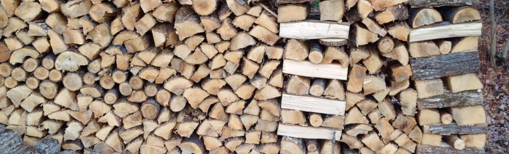 Carefull stacked firewood pile showing log ends and cross-stacking for stability.