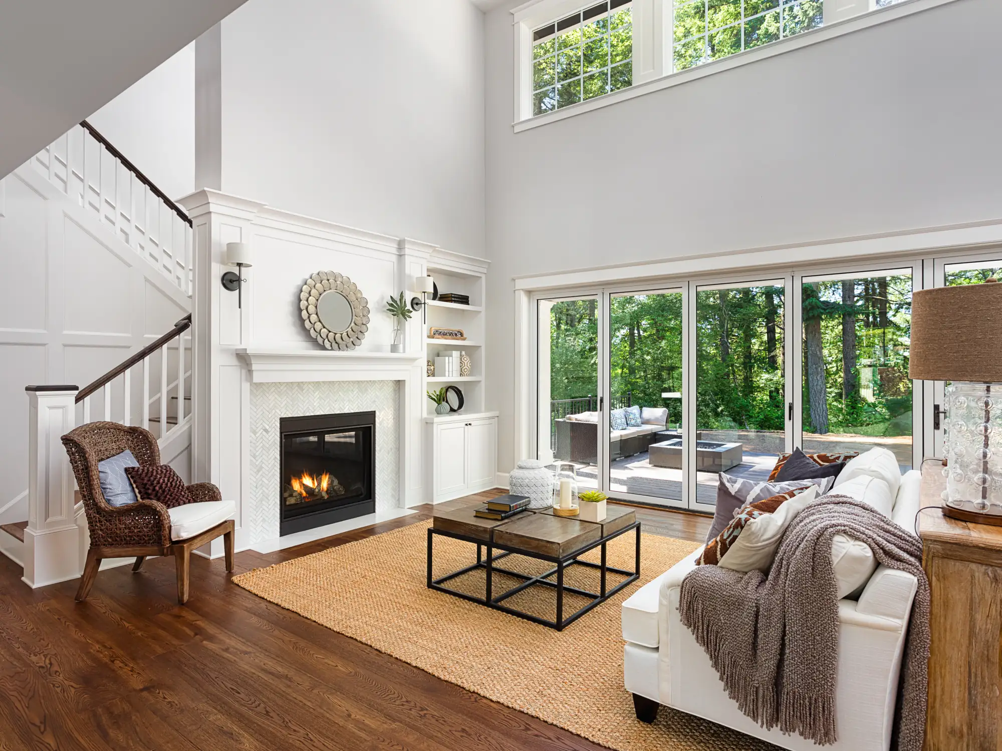 A large, bright Living Room interior with fireplace and lots of glass windows is a custom quality home interior.